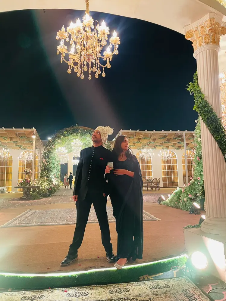 Harsh and partner beneath a chandelier
