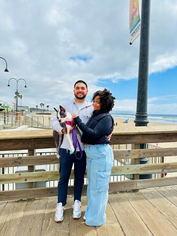 Jalyn, her husband and their dog on a pier at the beach.