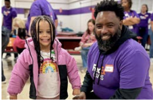 child wearing new coat next to FedEx volunteer