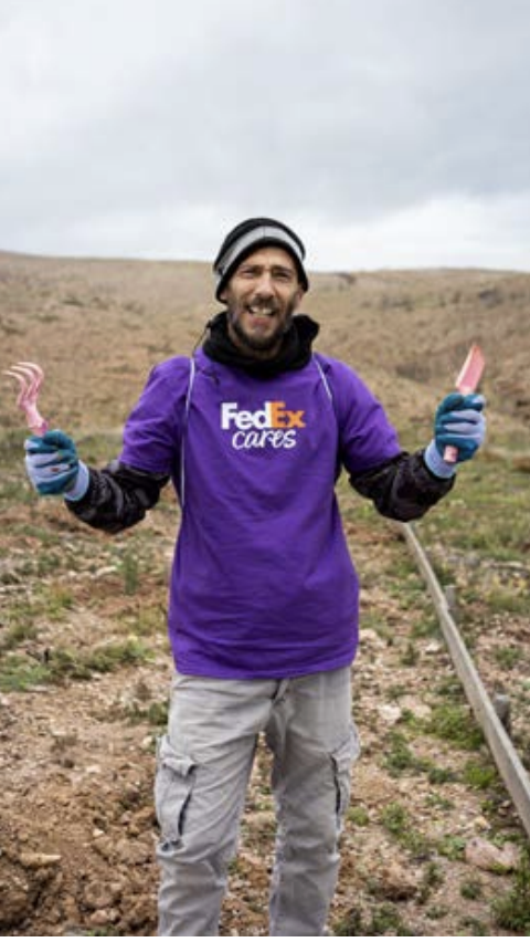 Person wearing FedEx shirt holding gardening tools