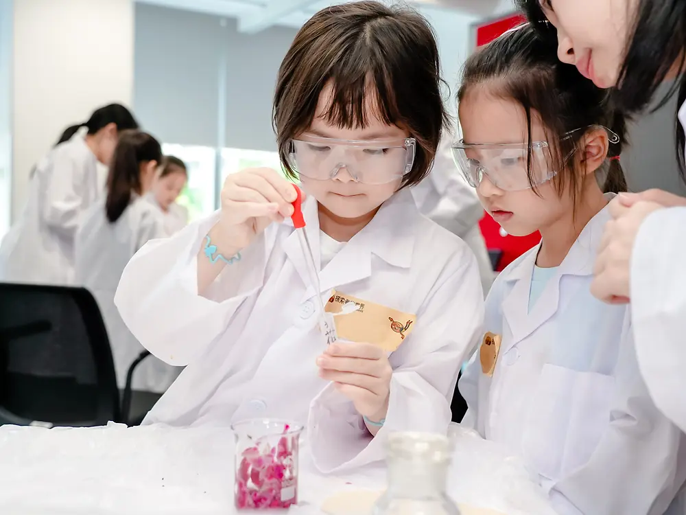 2 students in white coats performing experiments