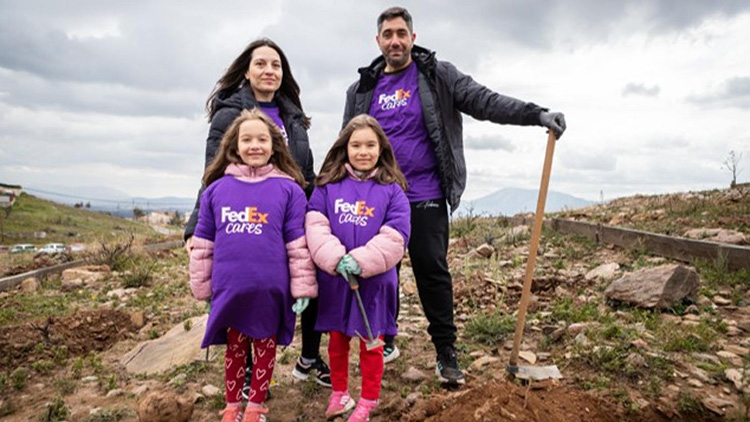Two children and two adults posing while planting on a hill