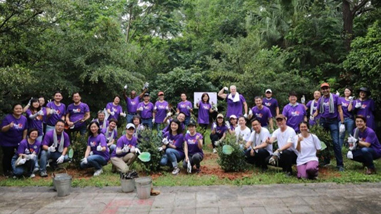Large group posing outside at planting area