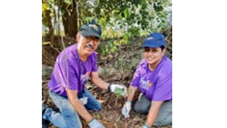 two smiling volunteers holding a plant