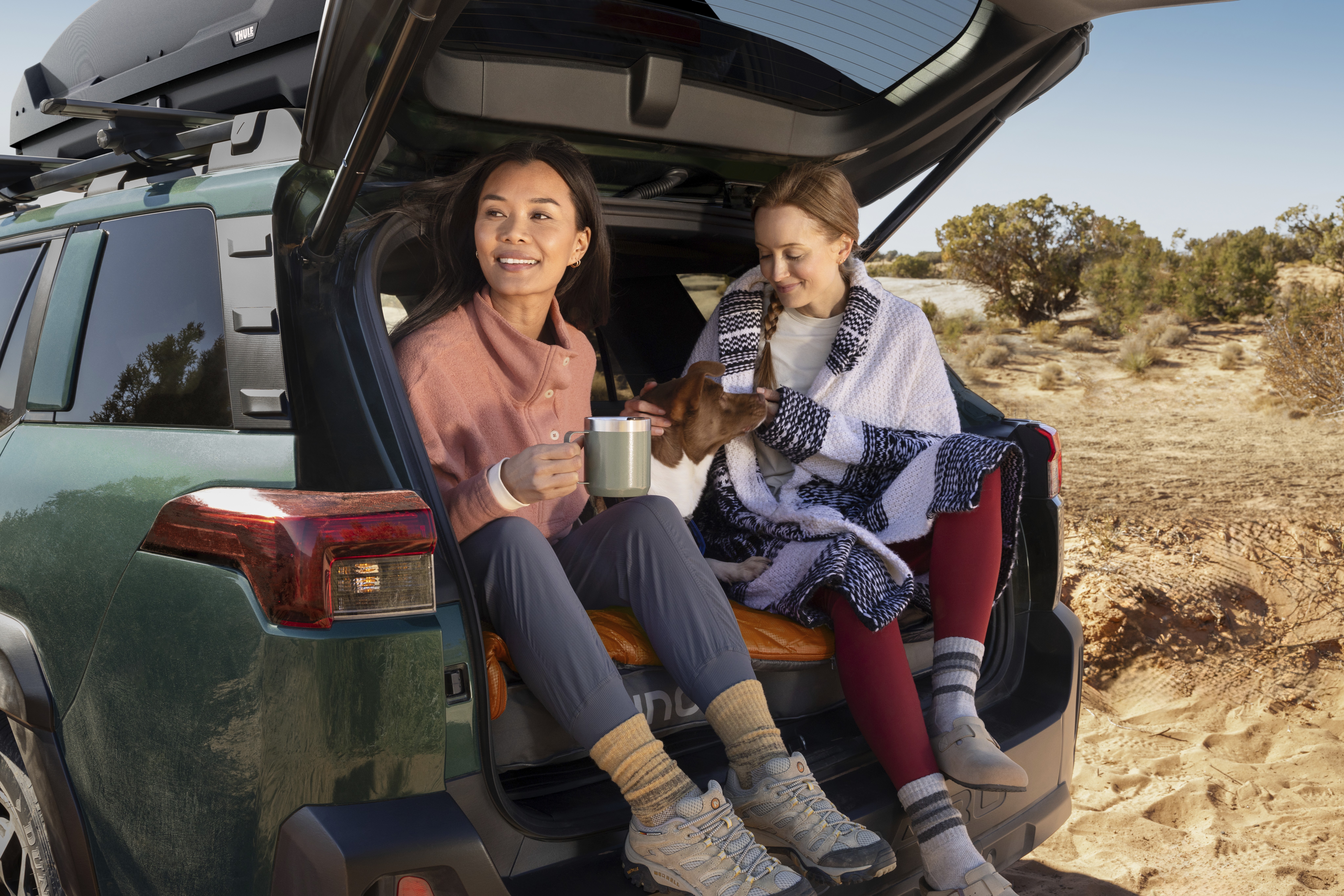 Two people sitting in the back of an open Subaru