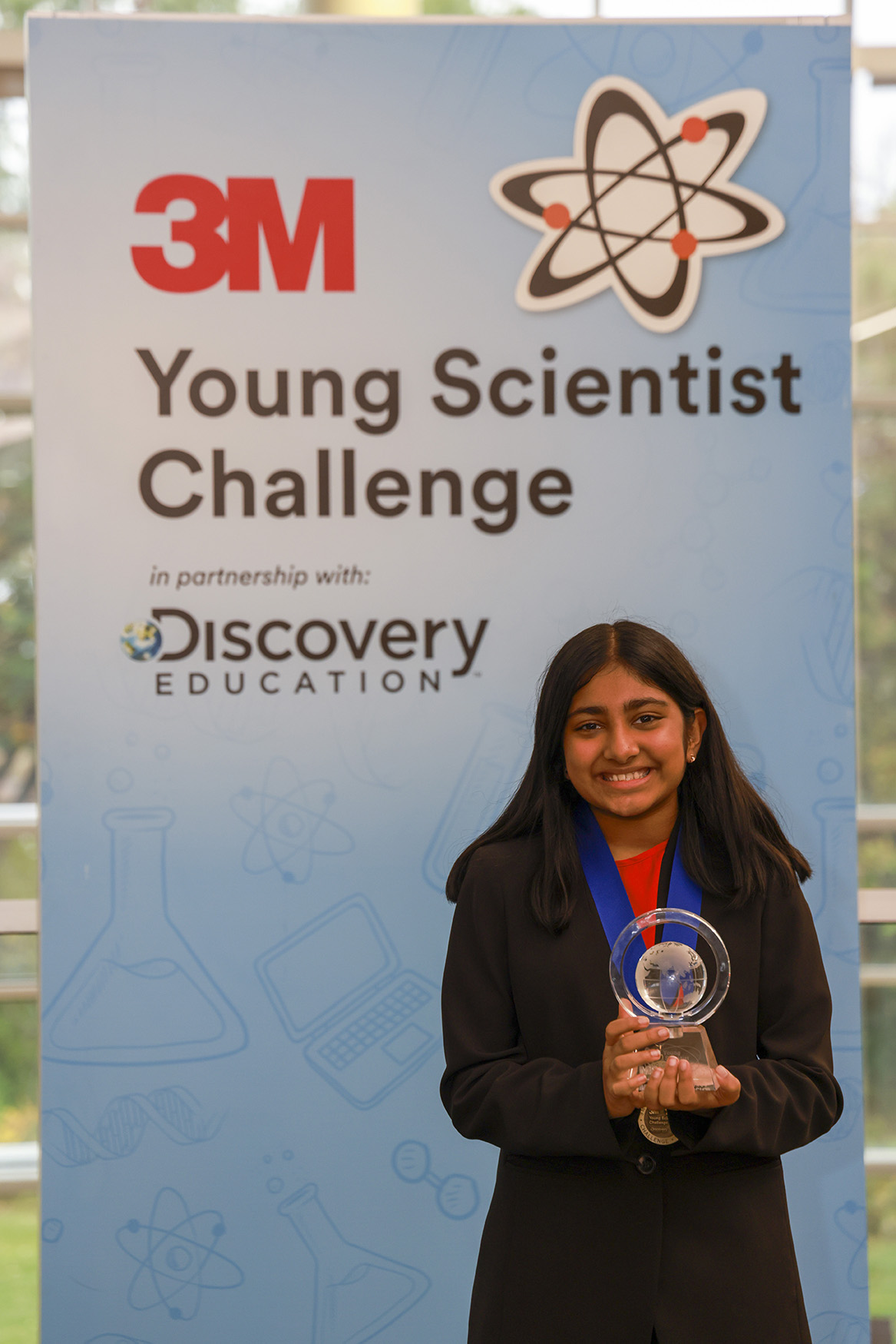 Raji Doshi in front of a 3M Young Scientist Challenge poster
