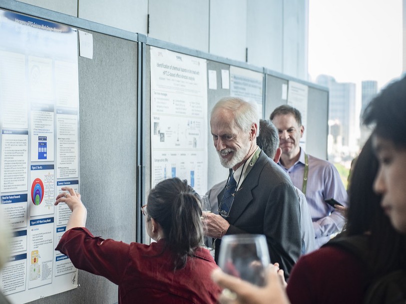 A researcher discusses her poster presentation with an attendee
