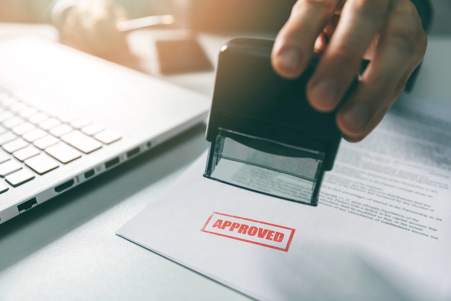 Paper being stamped with the word "Approved"