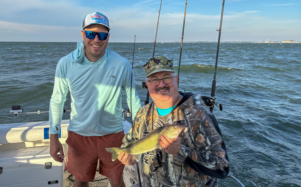 Detroit refinery Machinery & Mechanical Supervisor Levi Topp stands with Vets with Nets participant Marc Delaney, who is holding his first walleye catch for the day.