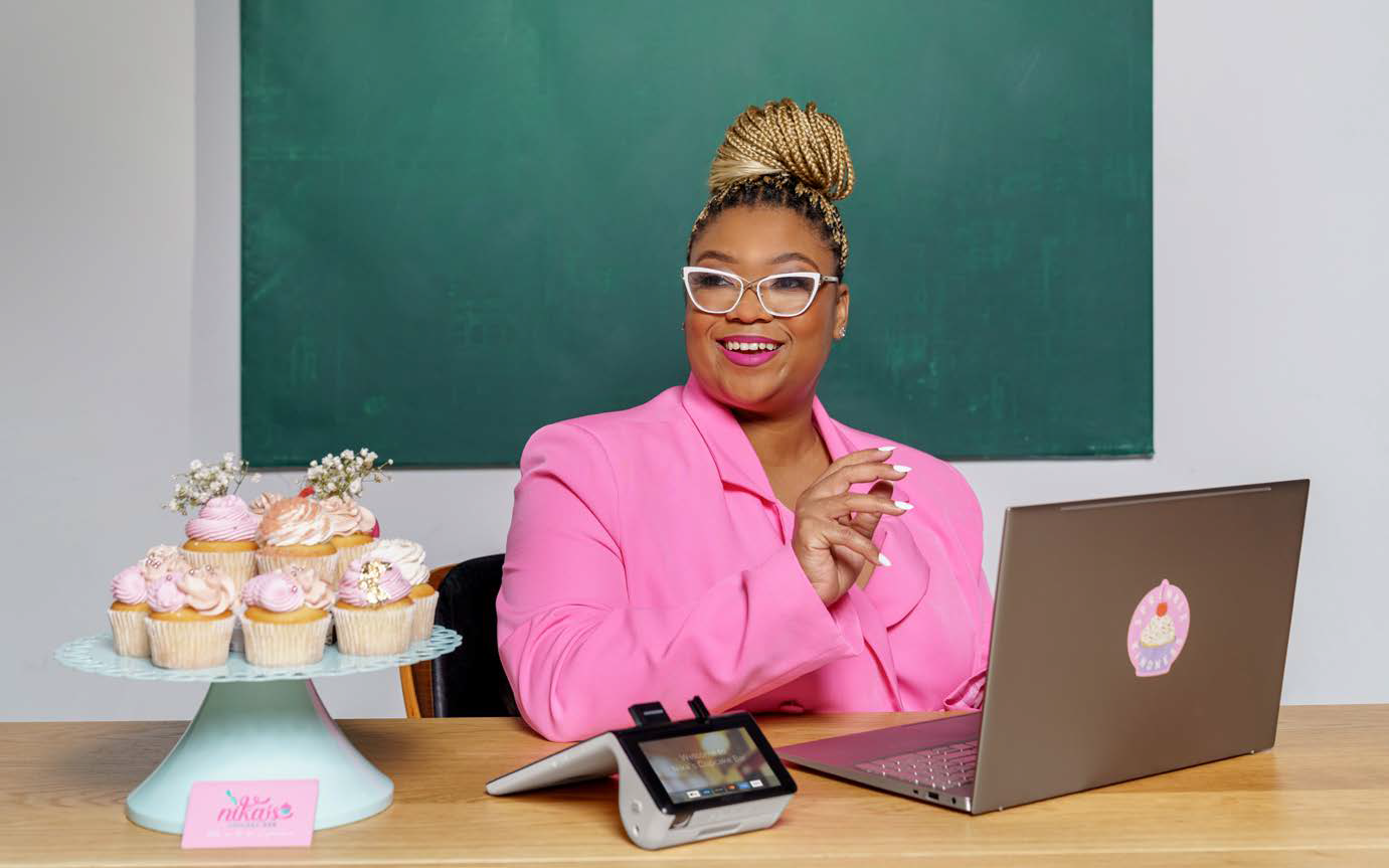 Entrepreneur dressed in pink next to a plate of pink cupcakes