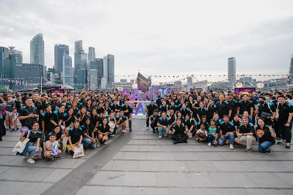 Large group photo, taken outside with city skyline in background