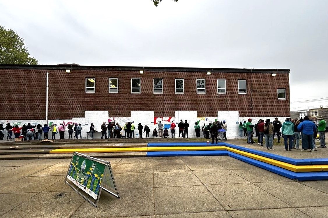 Volunteers painting a mural on a building