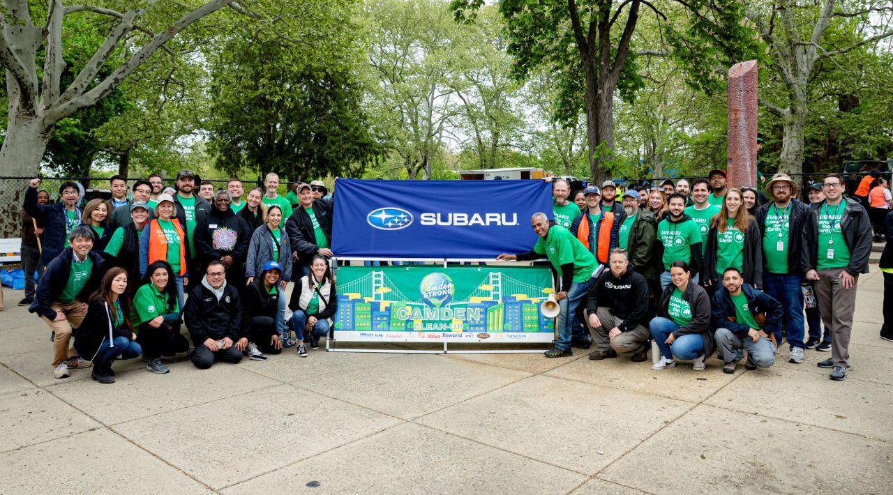 Group of volunteers posing with a Subaru banner and a Camden Clean-Up banner