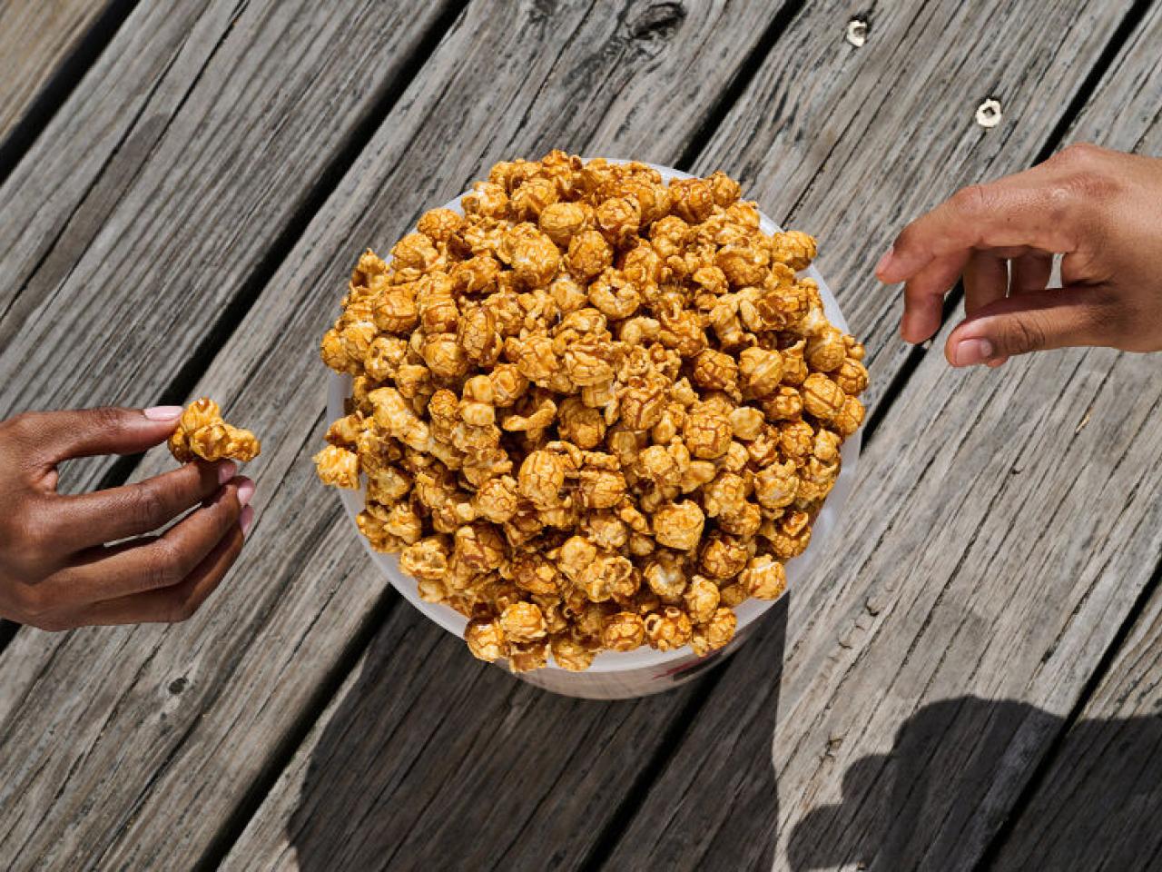 two hands reaching for caramel corn