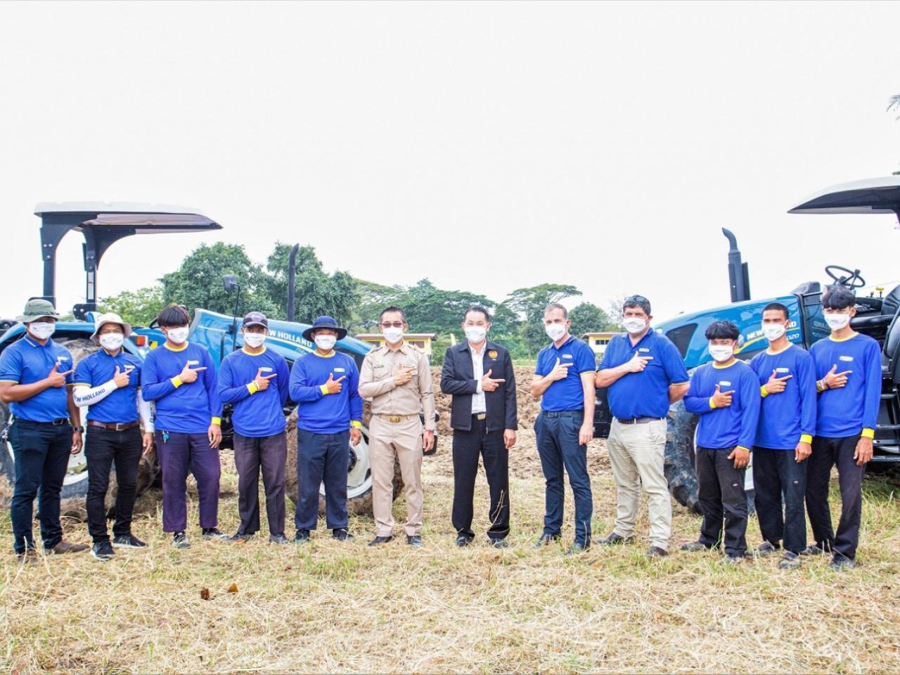Group of people posing in front of two tractors