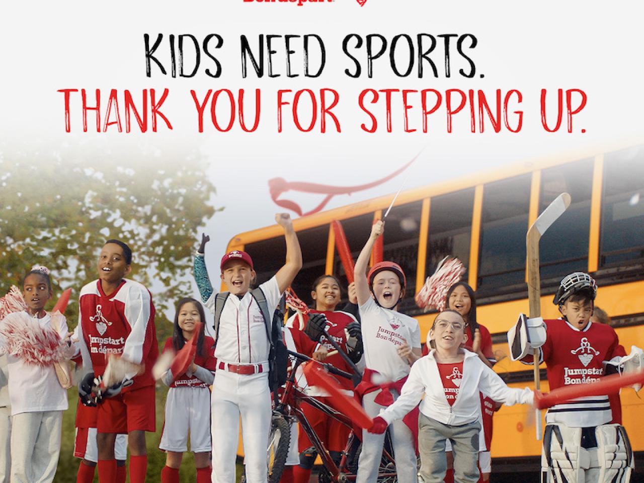 Kids Need sports thank you for stepping up. Kids shown in front of a school bus.