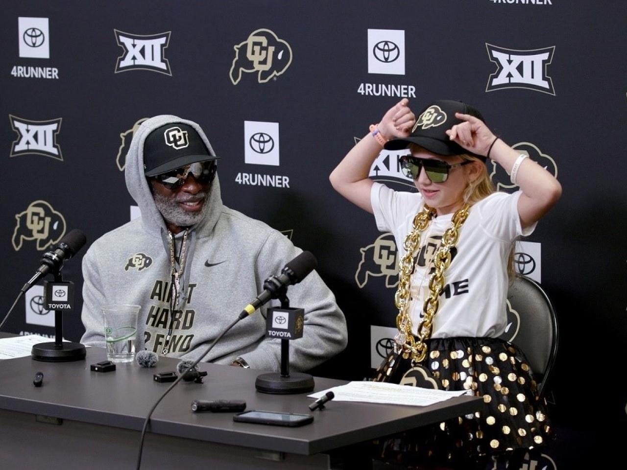Coach Prime and Piper seated at a table.