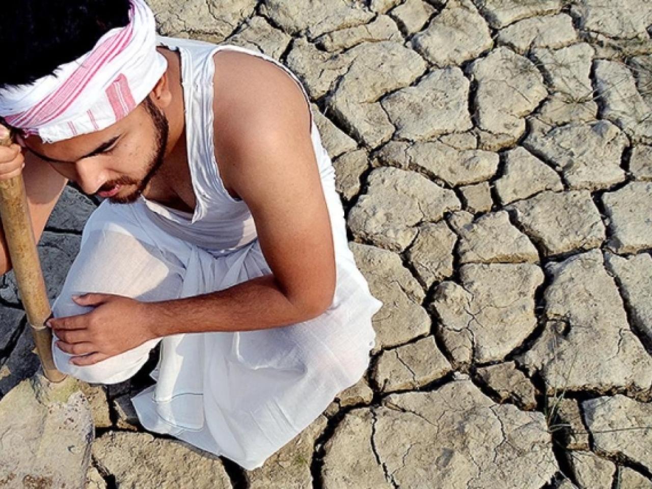 a person kneeling on cracked, dry soil