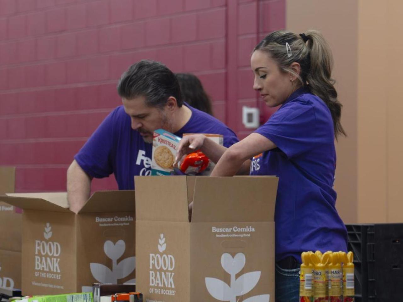 Two people wearing FedEx shirts packing boxes at the Food Bank