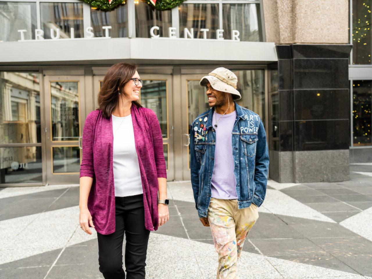 Two people walking out of a building smiling at each other