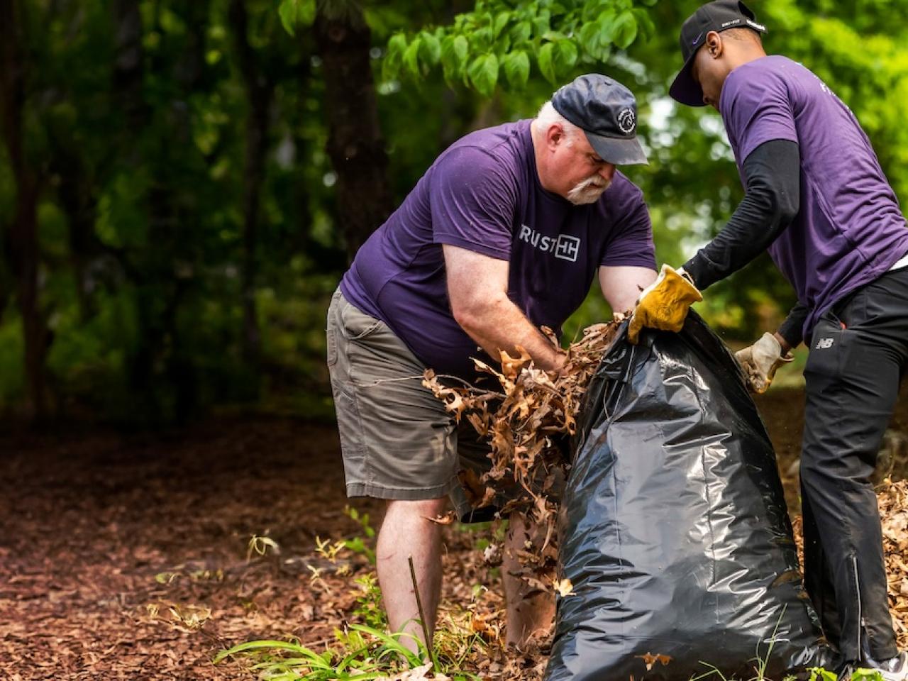 Two Truist volunteers stuffing debris into a bag.