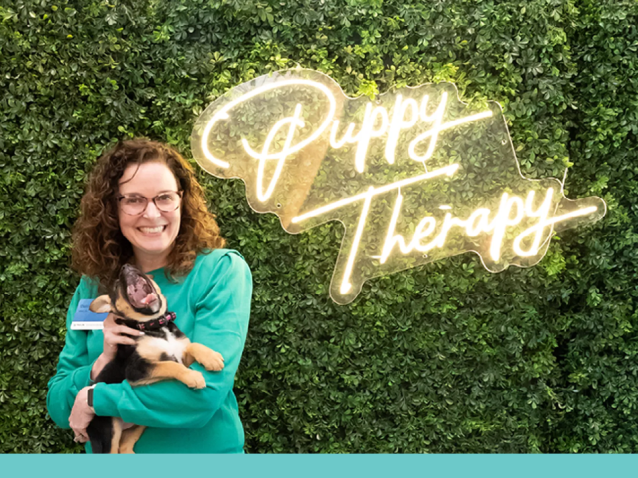 Woman holding dog with the words, "Puppy Therapy" behind them
