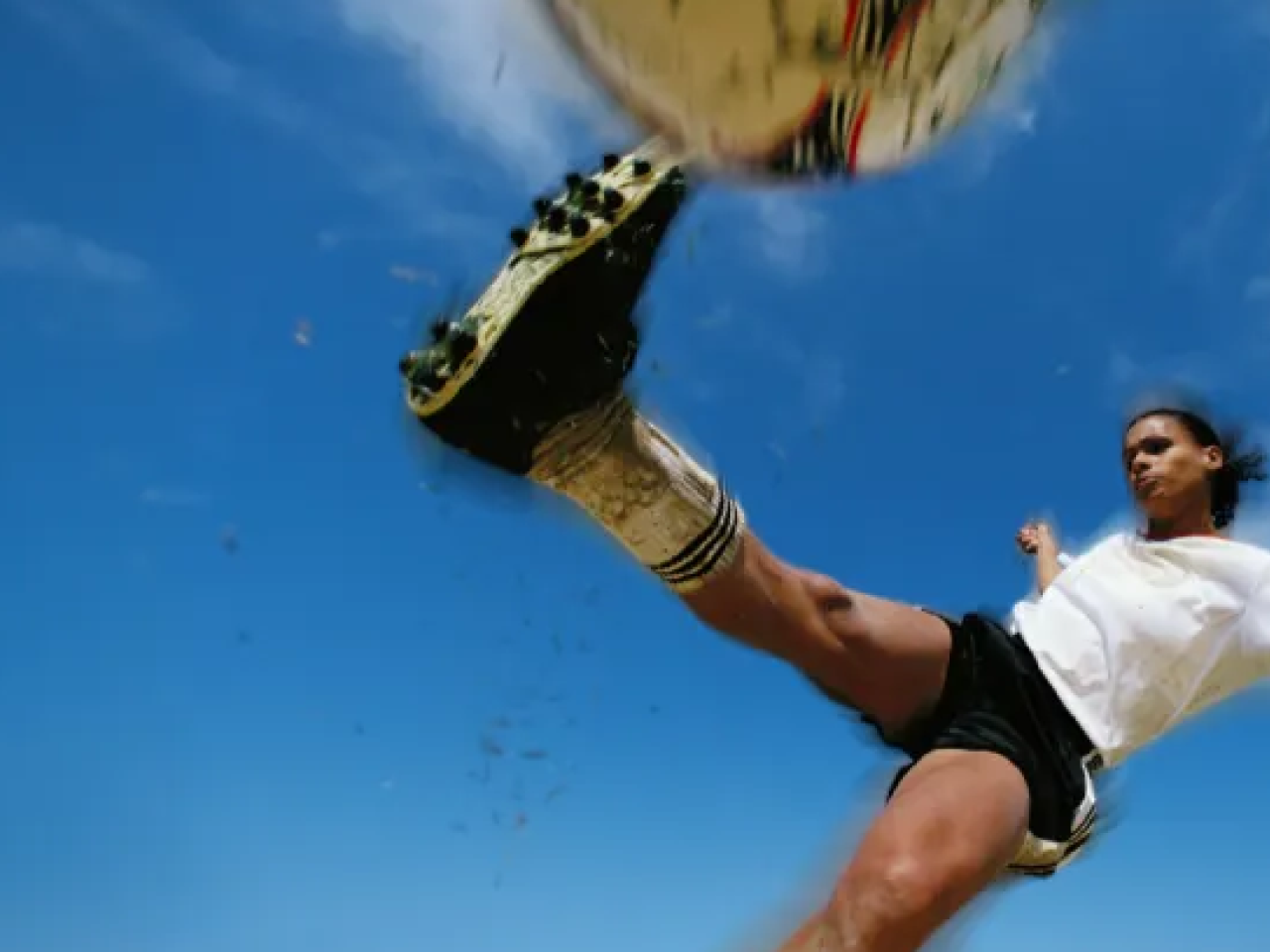 Female soccer player kicking a ball.