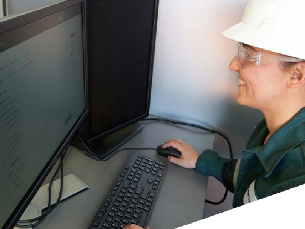 A person in protective gear working on a desktop computer.