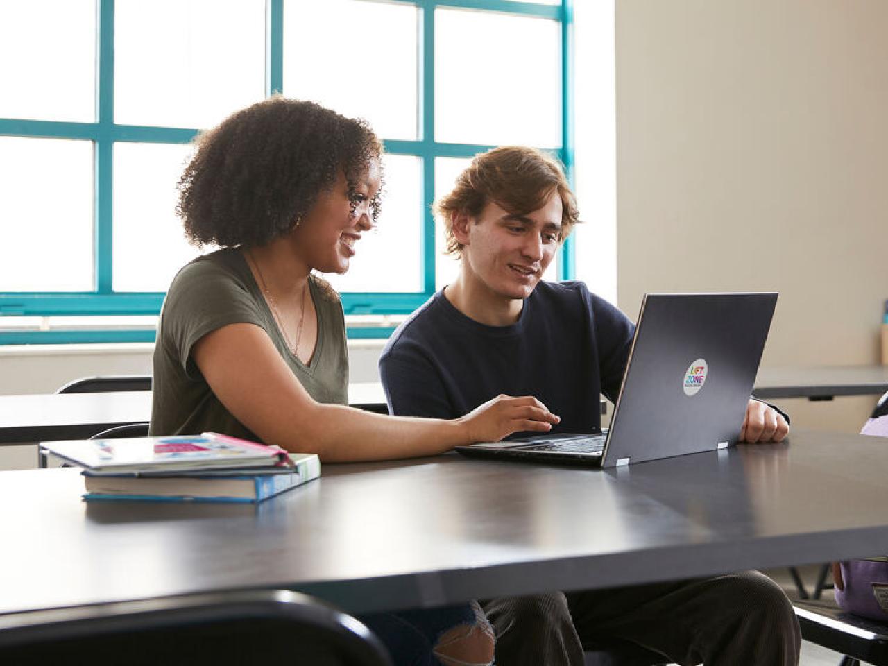 Two people working on laptop together 