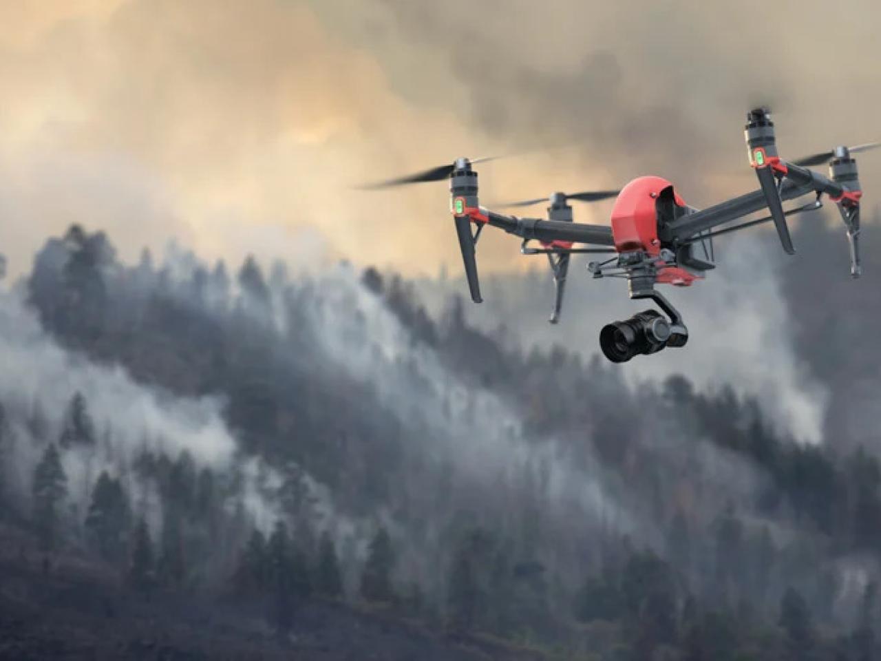 A drone flying over a smoke filled forest.