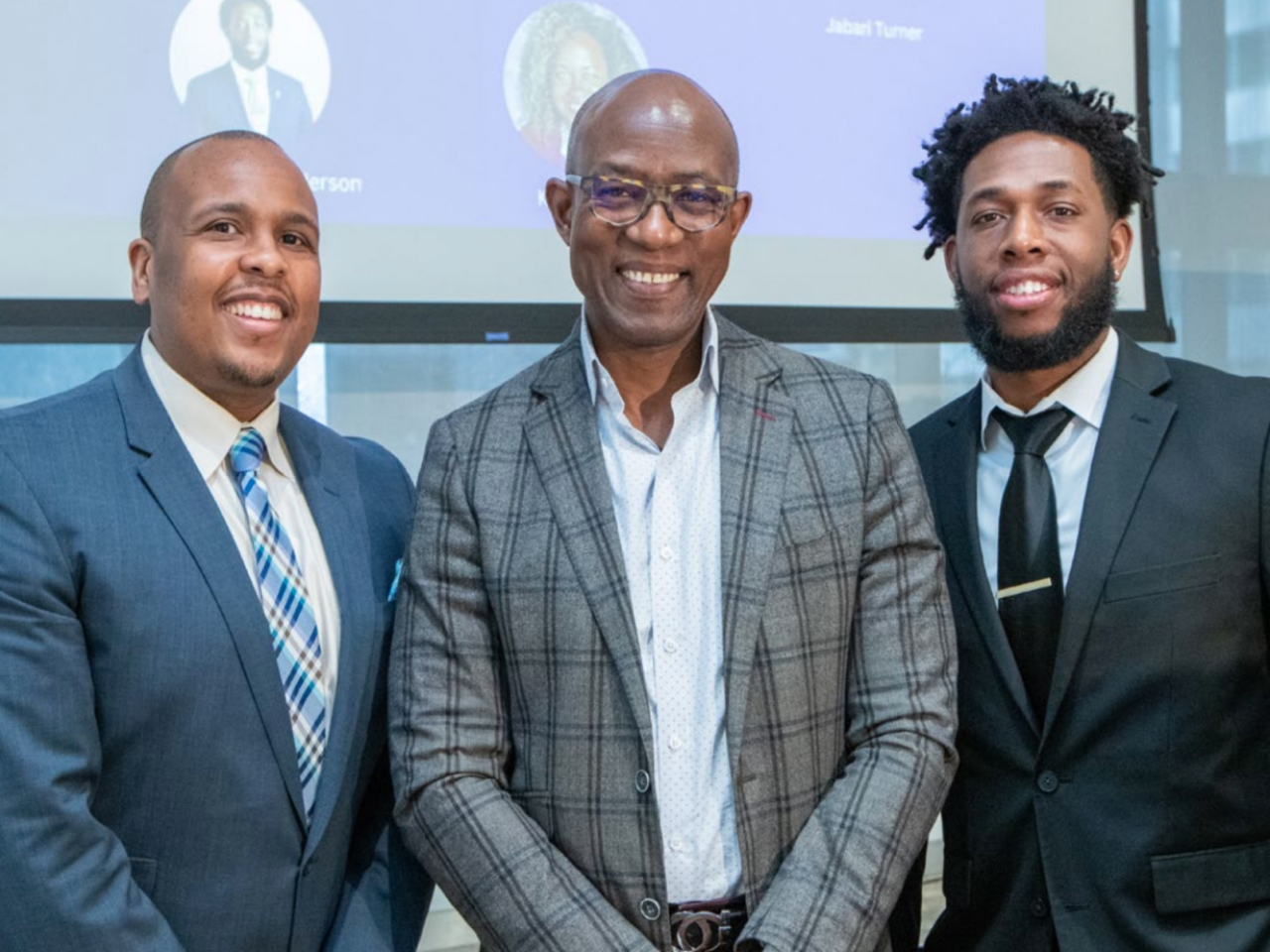 group of three black men in suits smiling