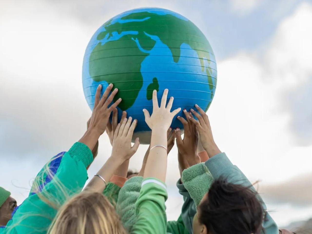 Hands holding up a globe outside