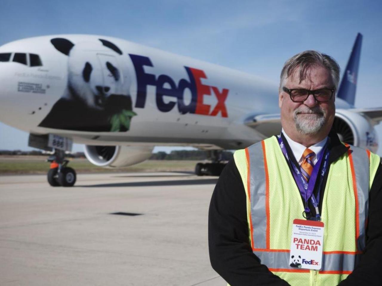 Dave Lange standing outside in front of a FedEx plane with a panda on the side.
