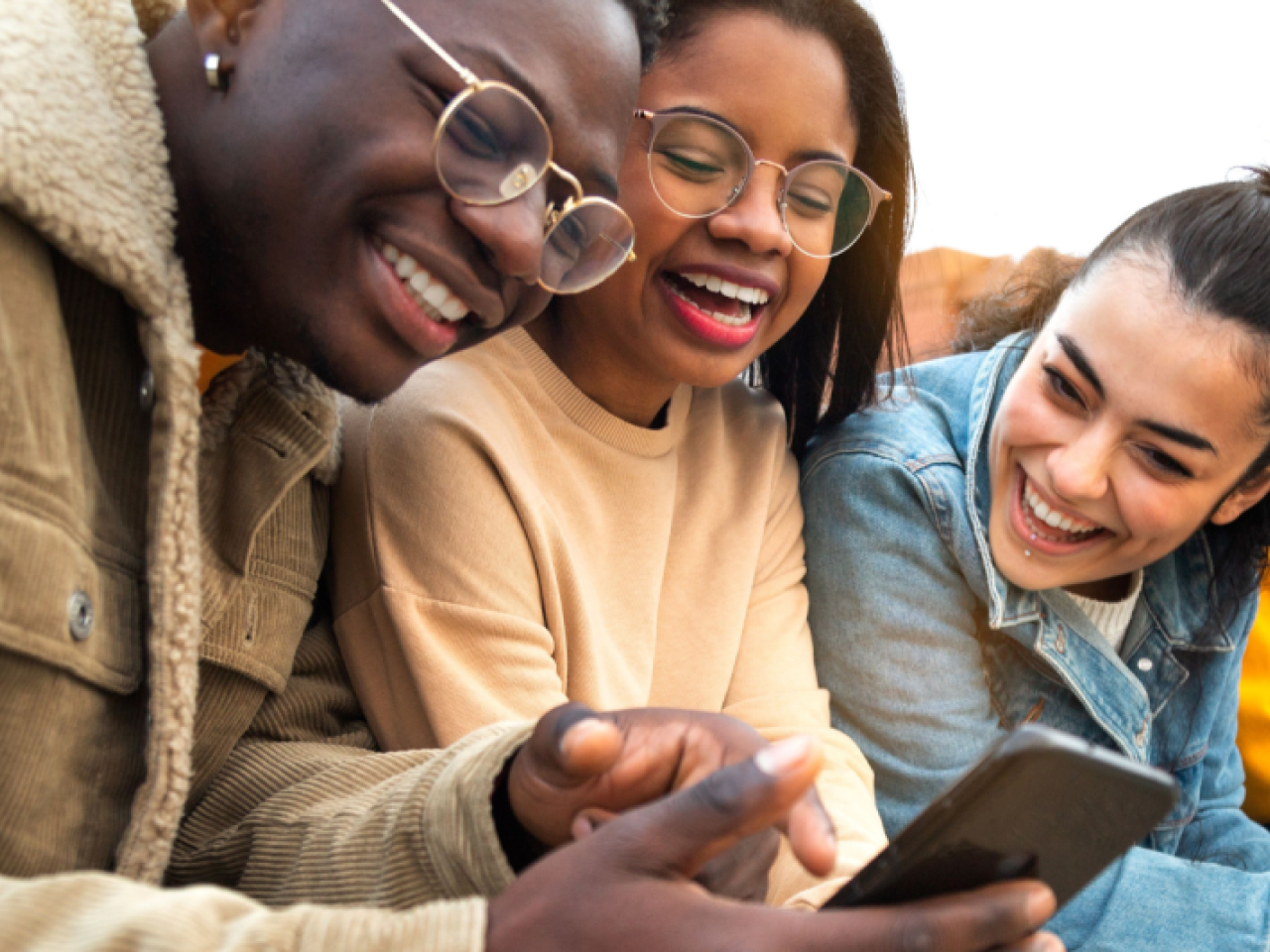 Three people look at a smartphone