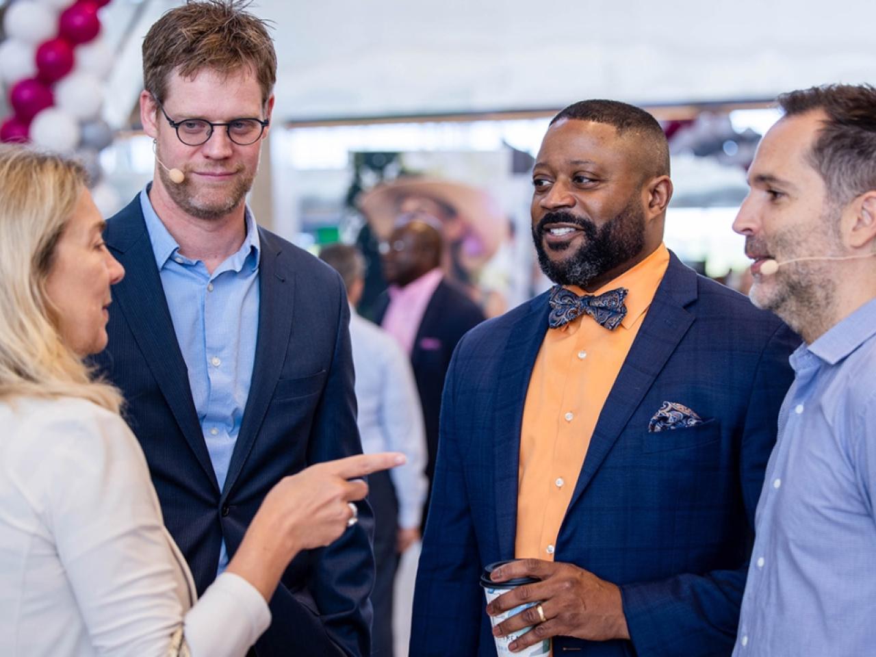 Four people standing in a group talking