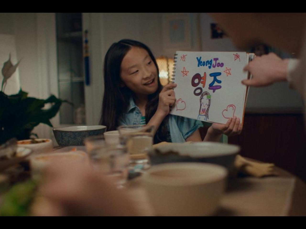 A child holding a hand drawn sign with their name on it.