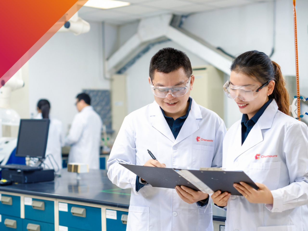 Two people in white coats looking at clipboard together