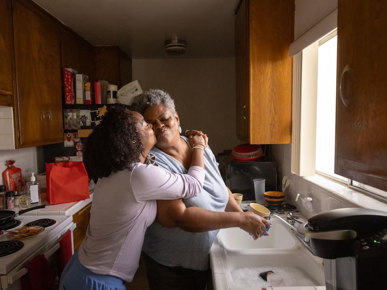 Two women hugging in a kitchen.