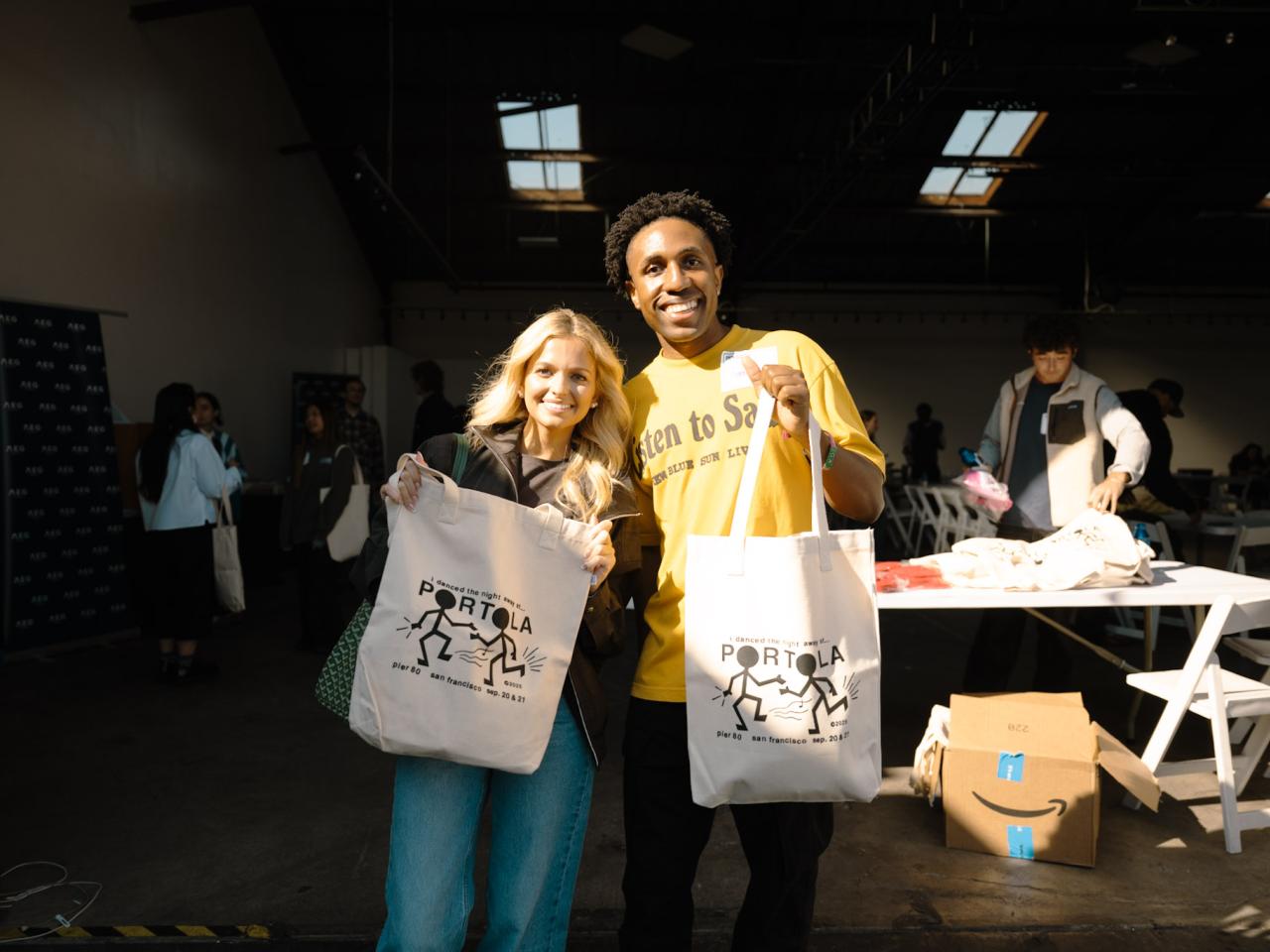 Two event participants pose with Portola-branded tote bags during the College Connection Program.