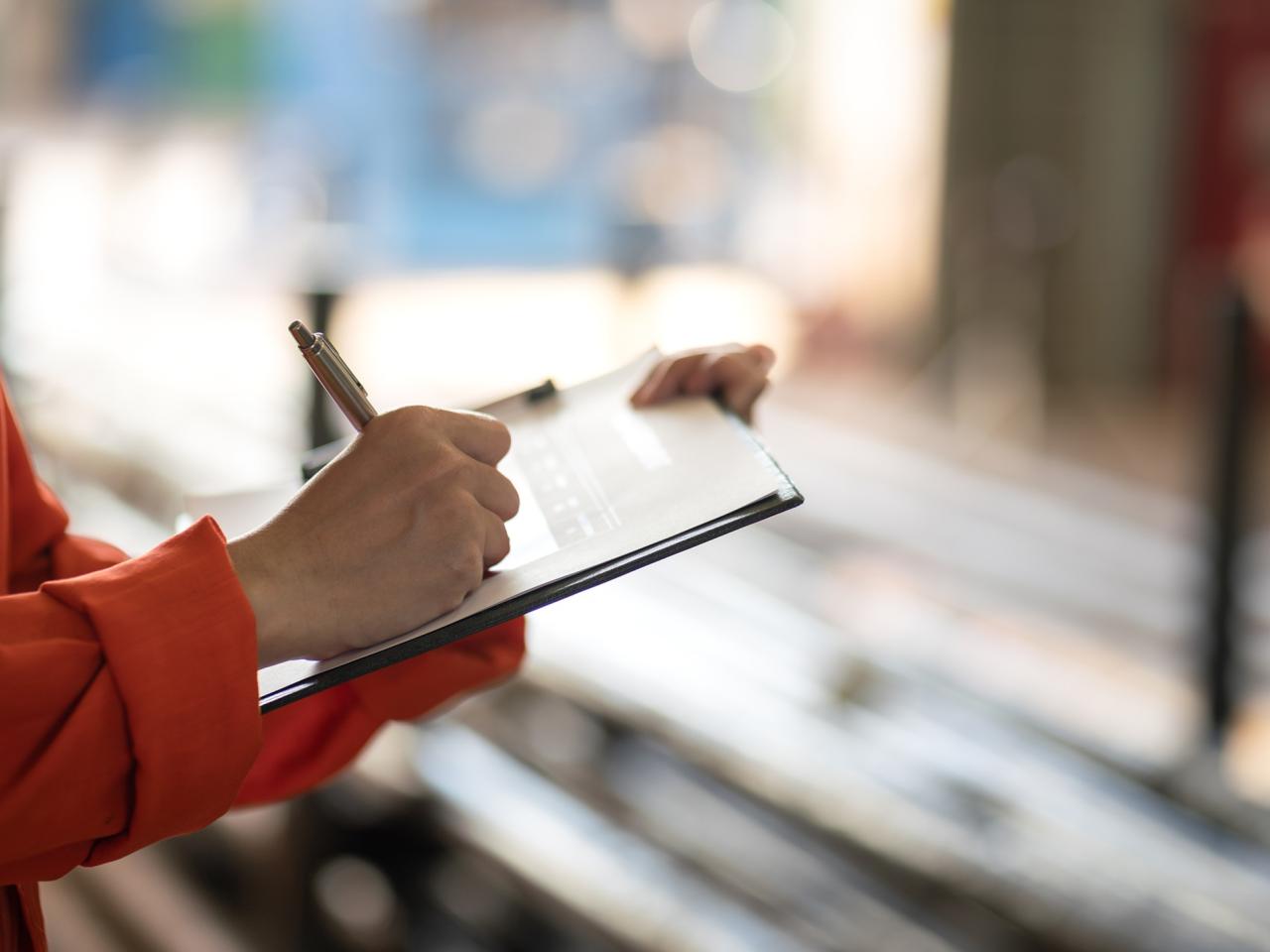 Worker in safety orange writing on a tablet