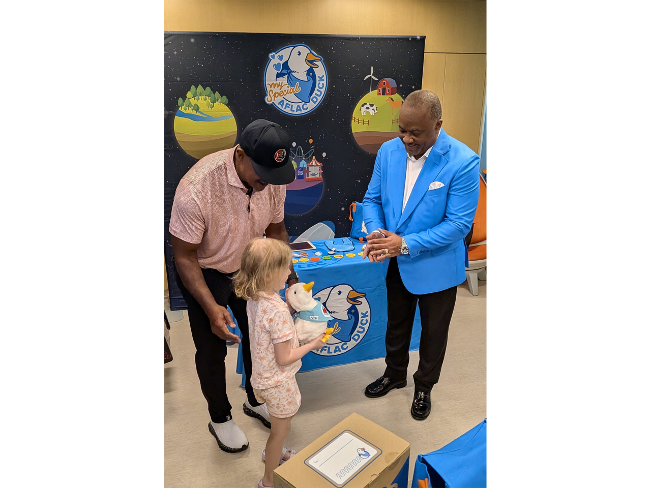 Former professional baseball and football player Brian Jordan (l) and Aflac Incorporated and Aflac U.S. President Virgil Miller (r) hand a My Special Aflac Duck to Leighton, a six year old patient at SSM Health Cardinal Glennon Children's Hospital in St. Louis.