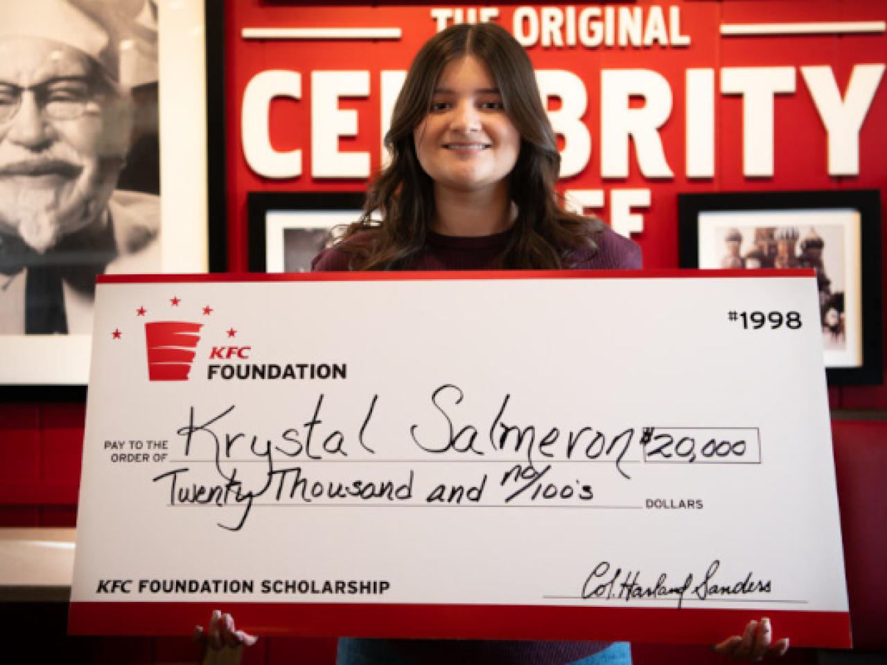 Scholarship recipient holding up check