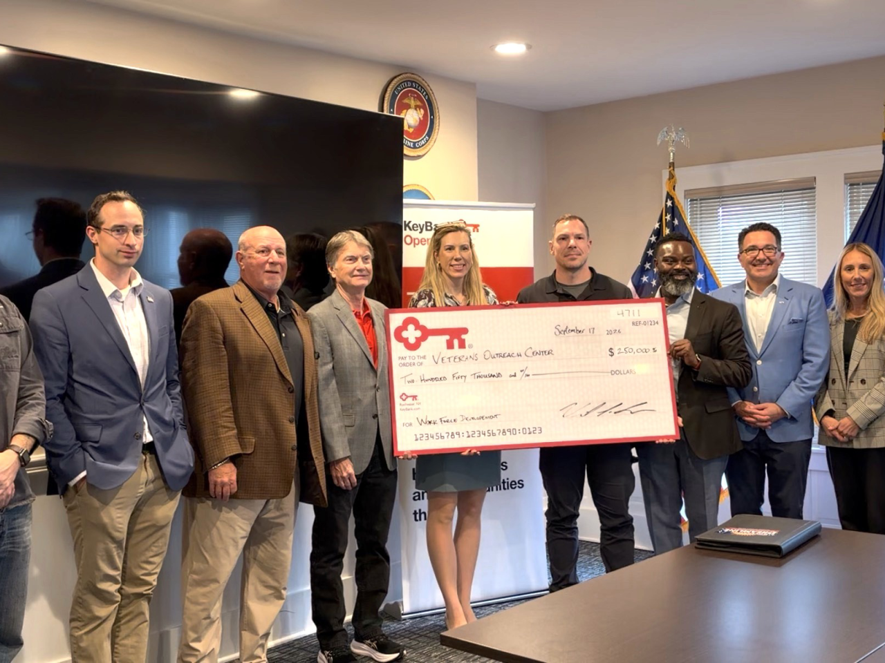 A small group standing together, holding an oversized check from KeyBank