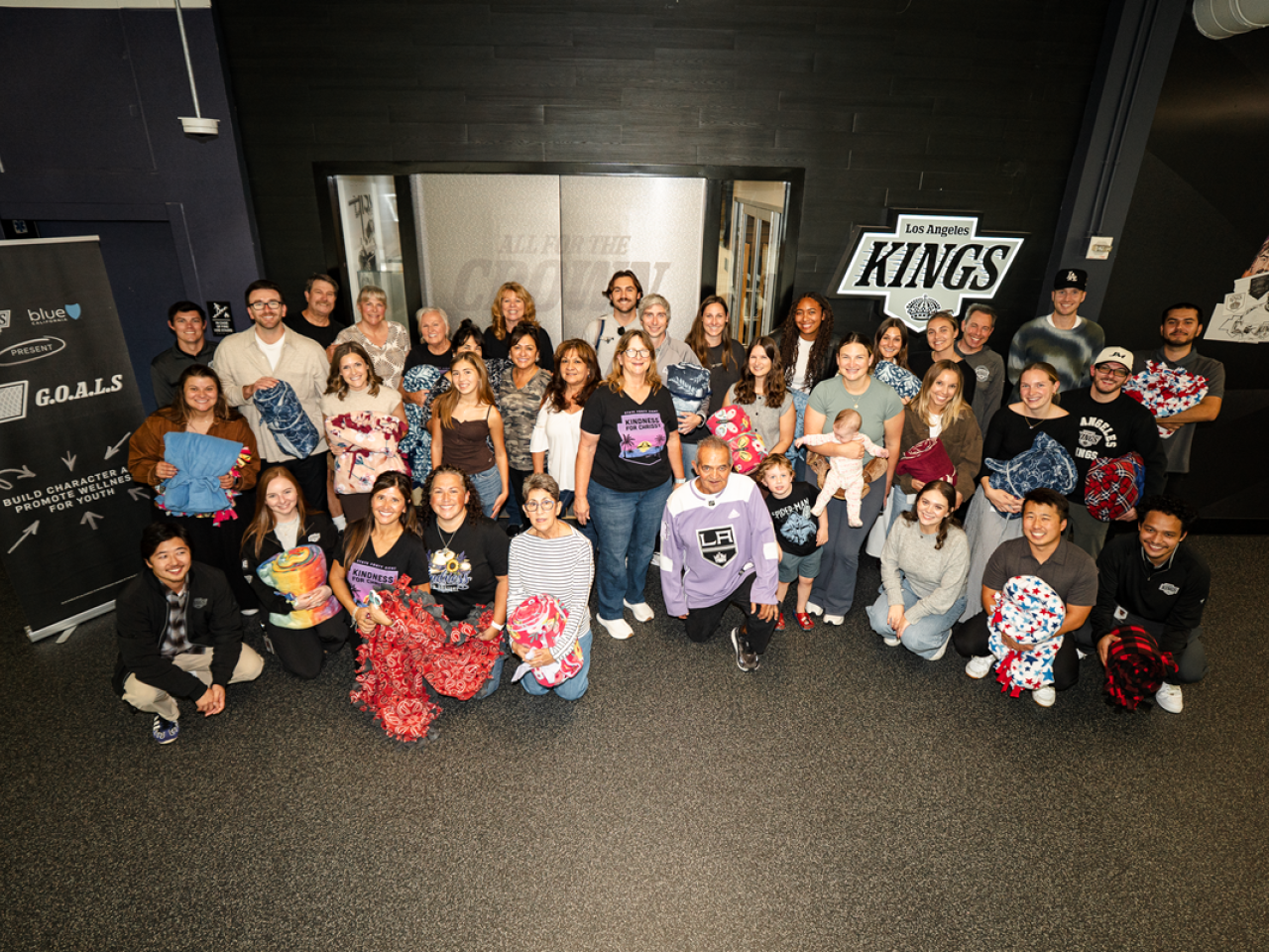 Volunteers pose for group photo in front of the Kings office with blankets made 