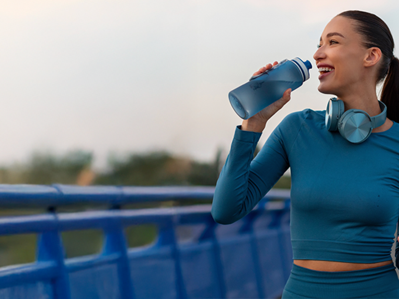 A person walking on a bridge with a water bottle.