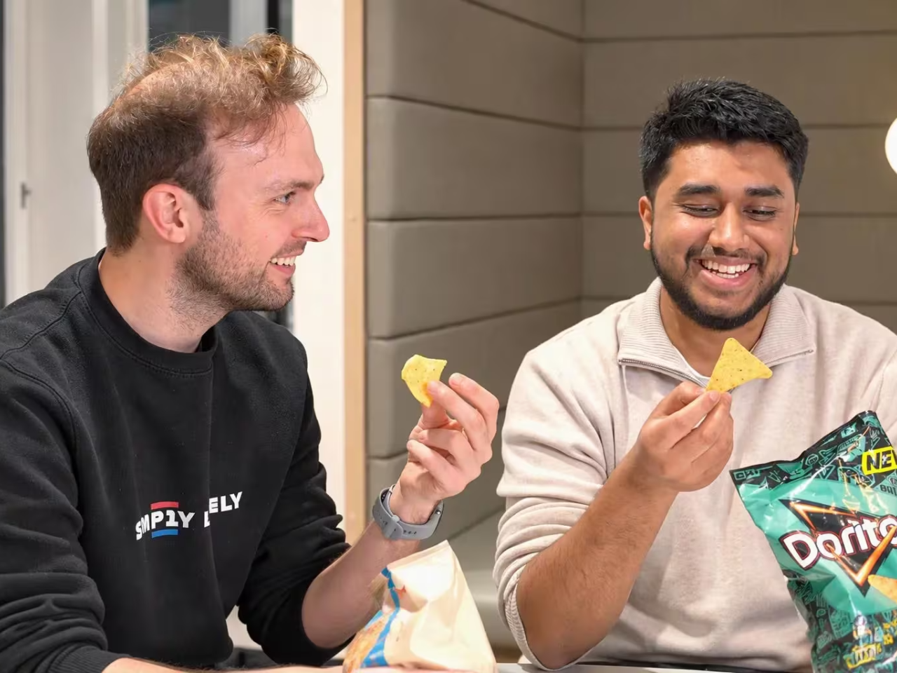 two smiling people eating Doritos