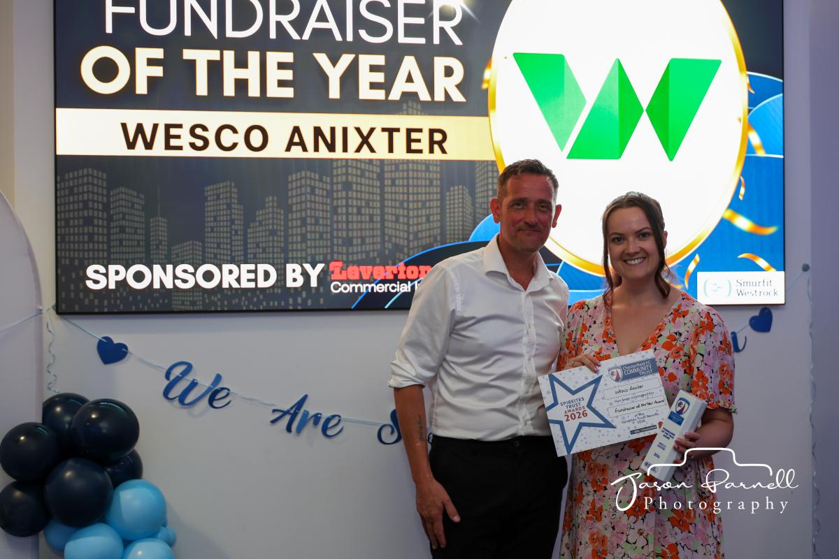 Man and woman standing in front of Wesco logo