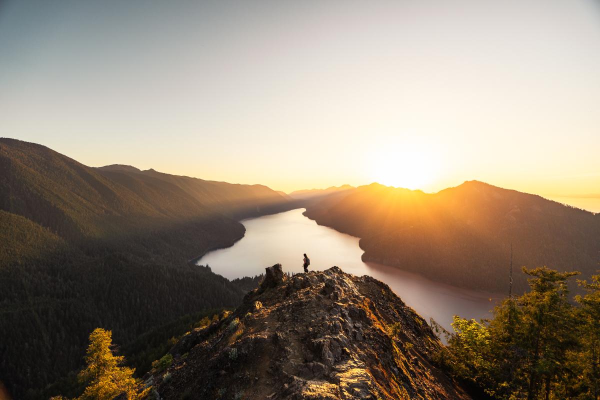 Aerial shot of someone hiking in the mountains high above a body of water