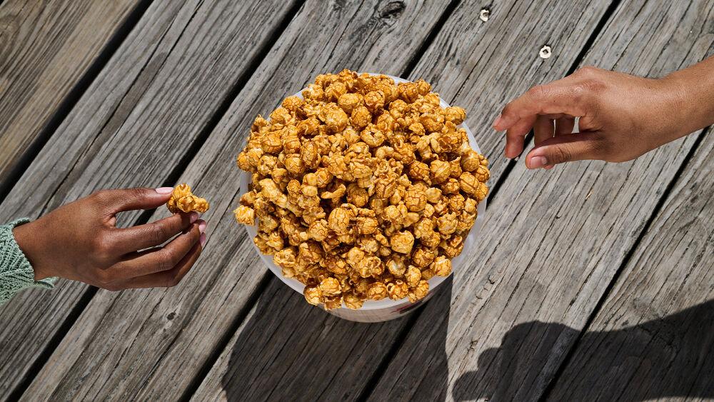 two hands reaching for caramel corn