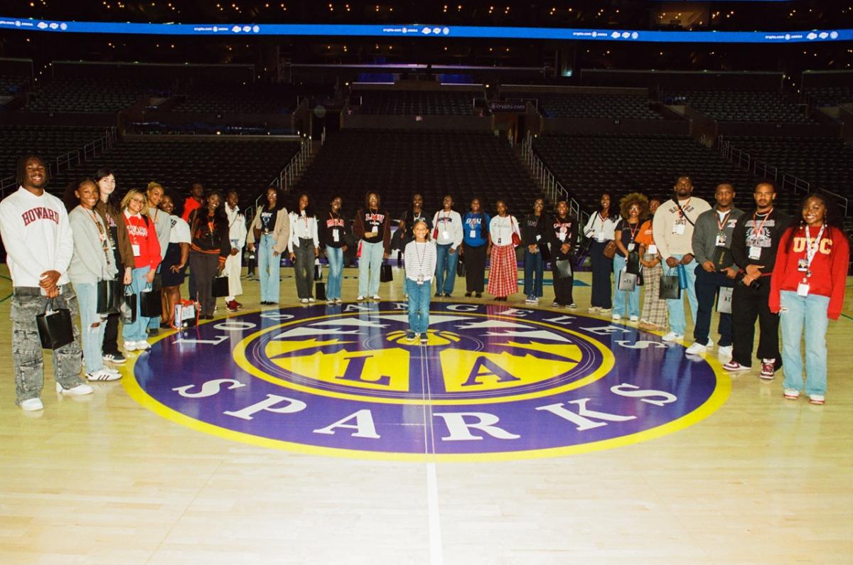 Group of students and professionals standing on the Los Angeles Sparks basketball court for a photo inside Crypto.com Arena.